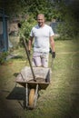 man pushing wheelbarrow. Young man pushing a wheelbarrow on the farm.. vignetting Royalty Free Stock Photo