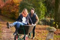 Man Pushing Woman In Wheelbarrow As Couple Rake Autumn Leaves From Garden Together Royalty Free Stock Photo