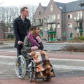 Man pushing a woman in a wheelchair at a zebra crosssing Royalty Free Stock Photo