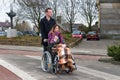 Man pushing a woman in a wheelchair at a zebra crosssing Royalty Free Stock Photo