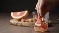 man put grapefruit into tumbler glass on wood table Royalty Free Stock Photo