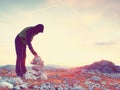 Man put the last stone intopeak of pyramid. Balanced stone pyramid on mountain summit. Royalty Free Stock Photo