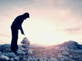 Man put the last stone intopeak of pyramid. Balanced stone pyramid on mountain summit. Royalty Free Stock Photo