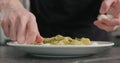 Man put mozzarella on pesto fettuccine in pasta bowl on concrete countertop