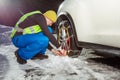 Man put on winter chains for car wheel at snowy road Royalty Free Stock Photo