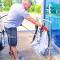The man puts active foam on the car Mat. Car wash. Self-service washing complex. High pressure car wash Royalty Free Stock Photo