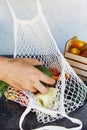 Man puts avocado to the eco shopping bag with fresh vegetables - tomatoes, purple potatoes, eggplants, carrots, sweet Royalty Free Stock Photo