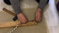 A man puts a bicycle chain on a nut and knocks out a pin. Uses a nail and a hammer. Makes the chain shorter, disconnects the link