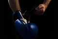 A man puts on a blue boxing boxing glove before a boxing fight on a black background