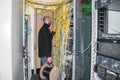 The man puts the cable in the server room. The technician works in the datacenter. The network engineer is next to a lot of wires