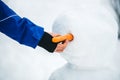 Man puts a carrot the a snowman figure, bodypart hand and arm