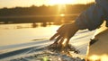 man puts fingers down lake kayaking against backdrop of golden sunset, unity harmony nature Royalty Free Stock Photo