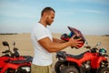 Man puts on helmet near atv in desert sands Royalty Free Stock Photo