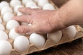 A man puts his hand on top of a cardboard tray of chicken eggs. Open recycled tray Royalty Free Stock Photo