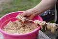 A man puts on raw pork meat for barbecue on skewers for cooking meat on a grilled fire