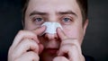 A man puts on and removes a strip for the nose from black dots. Coal cleaning strips from blackheads and comedones. The concept of