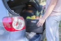 Man puts in the trunk of a car bag basket full of products