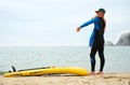 A man puts on a wetsuit on the beach and is going for a walk on the sea on a SUP board. Active recreation. Royalty Free Stock Photo