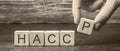 A man puts wooden blocks with the word HACCP. Hazard analysis and critical control points. Quality management rules for food Royalty Free Stock Photo