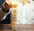 A man puts wooden blocks with the word Skills. Knowledge and skill. Self improvement. Education concept. Training. Leadership Royalty Free Stock Photo