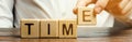 A man puts wooden blocks with the word Time. Concept of time management and proper distribution. Planning business and work.