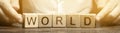 A man puts wooden blocks with the word World. The concept of globalization and global business. International relationships.