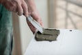 A man putsglue with putty knife on foam to stick it to the ceiling. Styrofoam, seiling mounting. Royalty Free Stock Photo