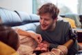 Man Putting Baby Shoes On Stomach Of Pregnant Partner With Prosthetic Arm At Home Royalty Free Stock Photo