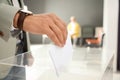 Man putting ballot paper into box at polling station