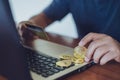 Man putting bitcoin into small shopping cart while using laptop. Royalty Free Stock Photo