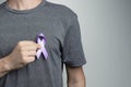 Man putting blue violet ribbon on shirt. Awareness symbol