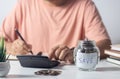 man putting coin in piggy bank and press the calculator with coins placed on the account book money saving concept Royalty Free Stock Photo