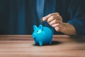 Man putting coin into piggy bank for saving money concept, business finance and investment Royalty Free Stock Photo