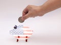 Man putting coin into piggy bank with USA flag Royalty Free Stock Photo