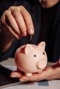 Man putting coin in pink piggy bank close-up. Saving money concept Royalty Free Stock Photo