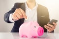 Man putting a coin into a pink piggy bank concept