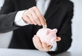 Man putting coin into small piggy bank