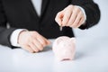 Man putting coin into small piggy bank