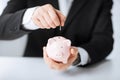 Man putting coin into small piggy bank Royalty Free Stock Photo