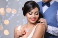 Man putting elegant jewelry on beautiful woman against blurred background Royalty Free Stock Photo