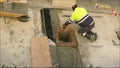 Man putting finaal touches to storm drain in village street