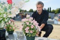 Man putting fresh flowers in graveyard Royalty Free Stock Photo