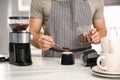 Man putting ground coffee beans into moka pot at table in kitchen, closeup Royalty Free Stock Photo