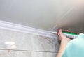 Man is putting gypsum baseboard with glue on ceiling. Maintenance repair works in the flat. Restoration indoors. Drywall panel Royalty Free Stock Photo