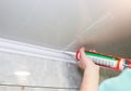 Man is putting gypsum baseboard with glue on ceiling. Maintenance repair works in the flat. Restoration indoors. Drywall panel Royalty Free Stock Photo