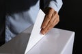 Man putting his vote into ballot box on black background Royalty Free Stock Photo