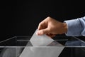 Man putting his vote into ballot box on black, closeup