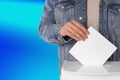 Man putting his vote into ballot box on color background, closeup Royalty Free Stock Photo