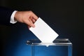 Man putting his vote into ballot box on dark blue background, closeup Royalty Free Stock Photo