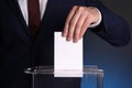 Man putting his vote into ballot box on dark blue background, closeup Royalty Free Stock Photo